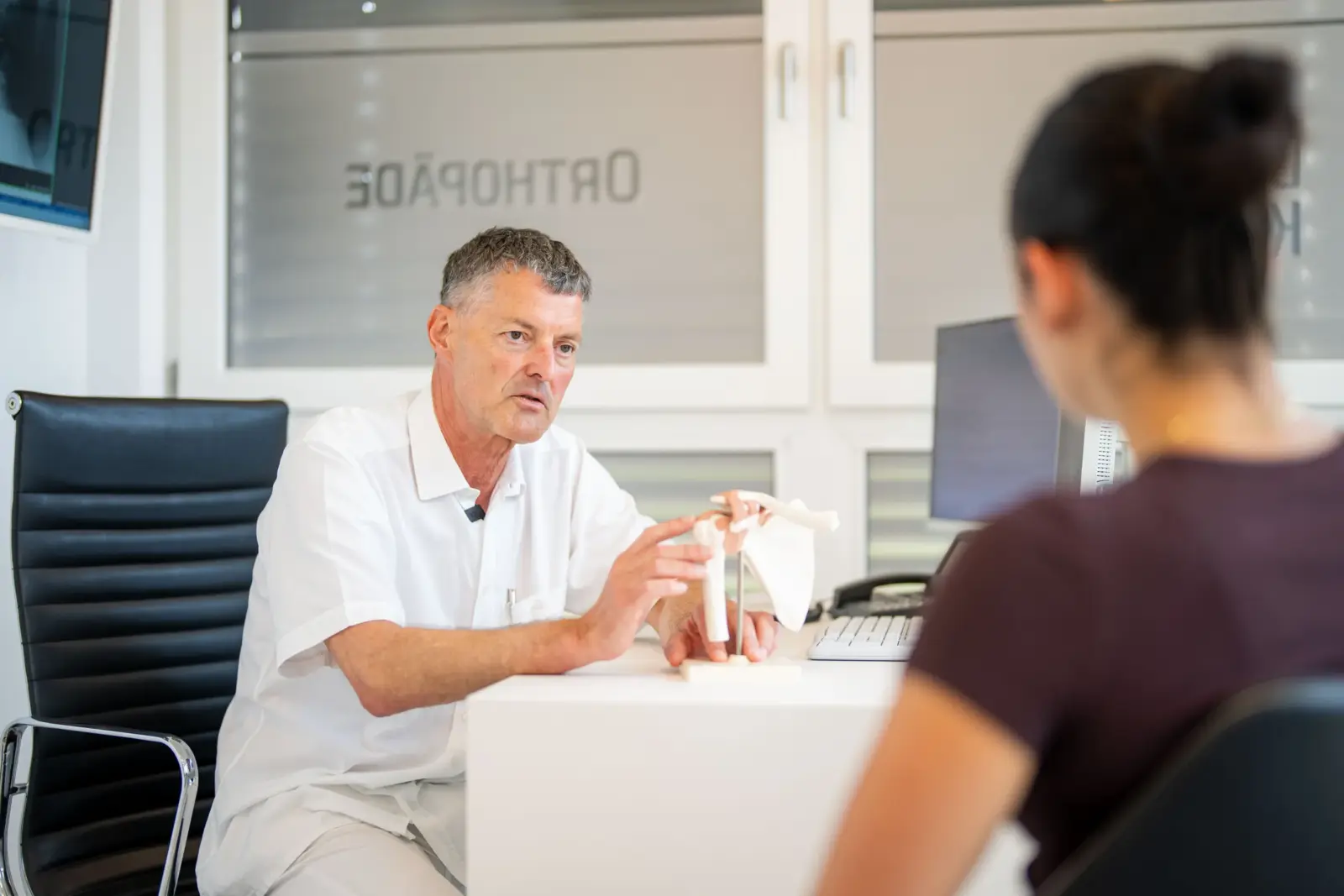 Dr. Knut Bär erklärt einer Patientin den Befund am Schultermodell