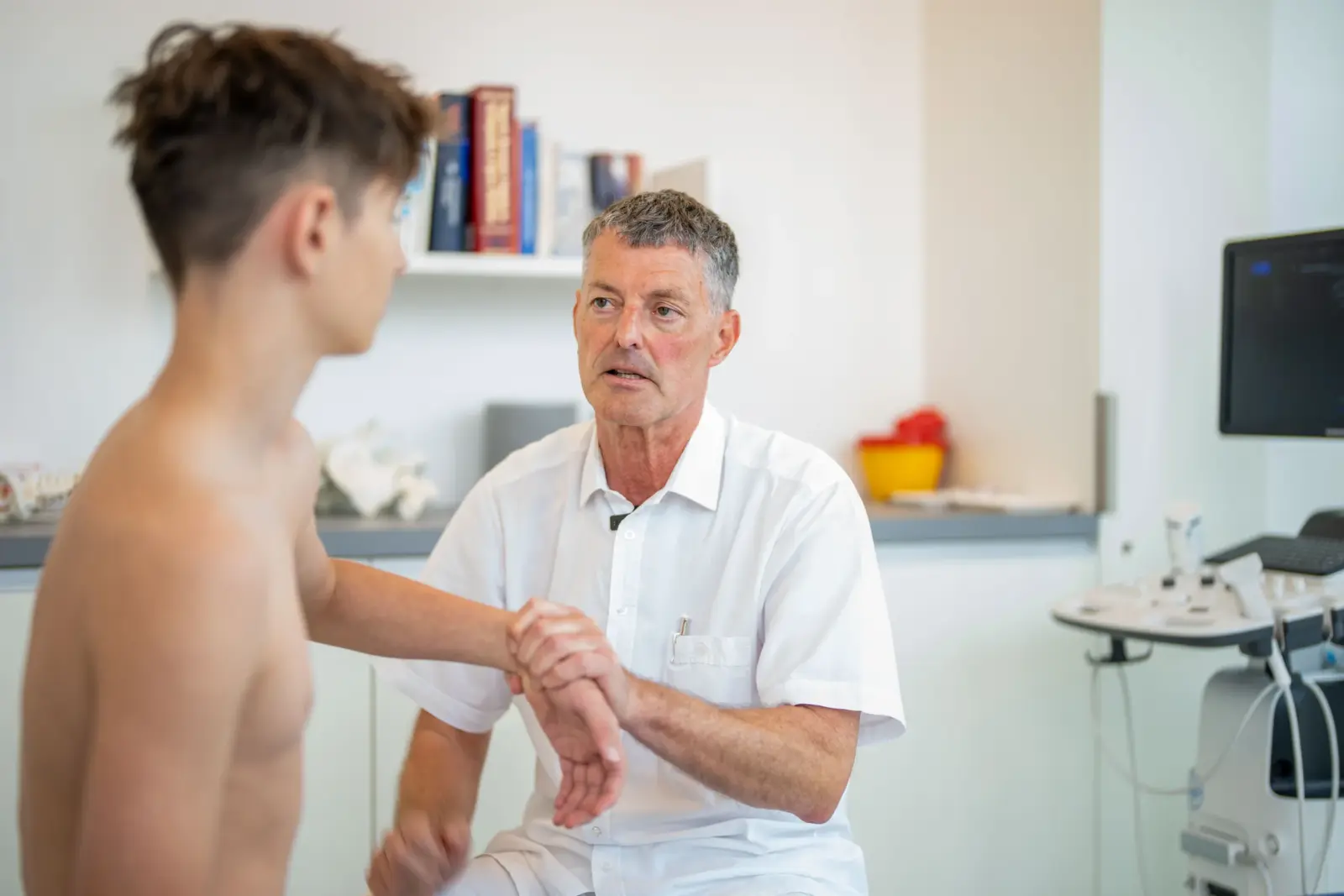 Dr. Knut Bär prüft Hand und Unterarm eines Patienten